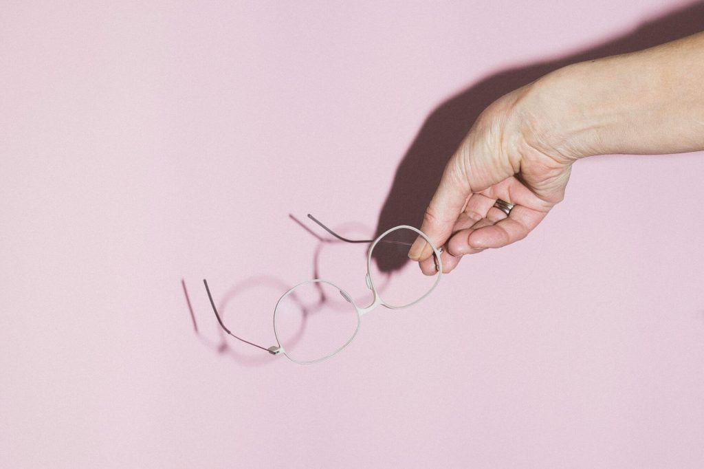 Eine Hand hält eine individualisierter 3D-Druck-Brille von weareannu vor rosa Hintergrund.